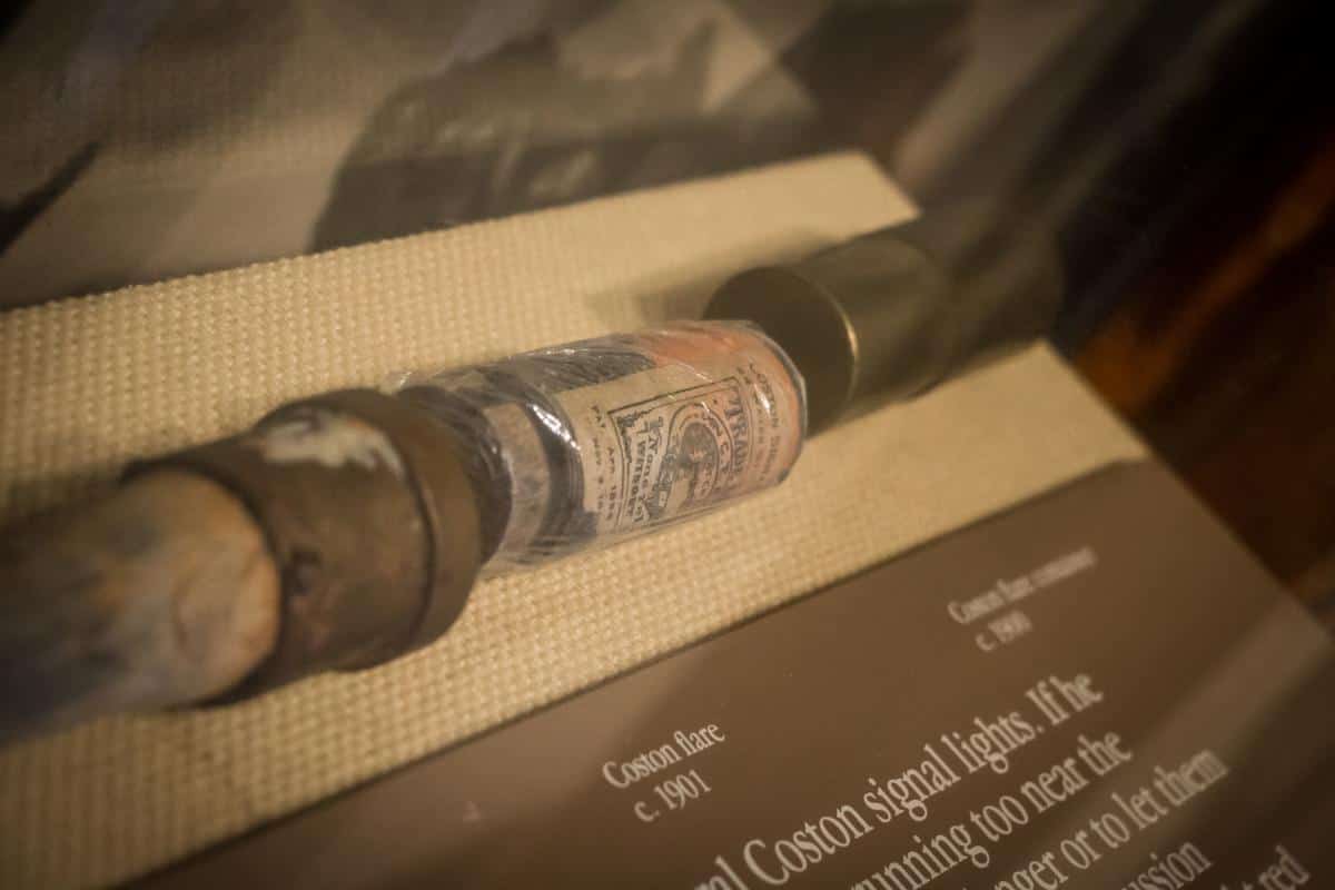 A vintage Coston flare from circa 1901 is displayed in a museum exhibit showcasing its historical use.