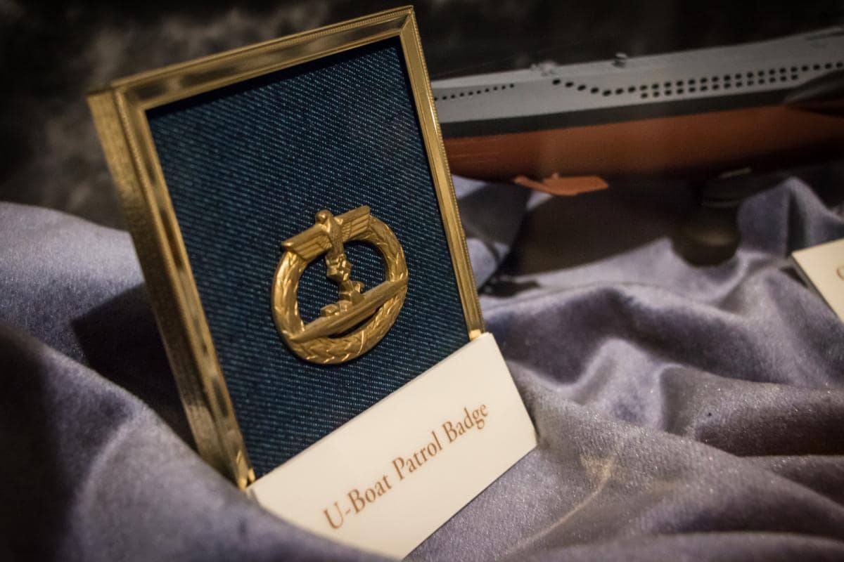 A gold U-Boat Patrol Badge is displayed in a small frame on a blue fabric background.