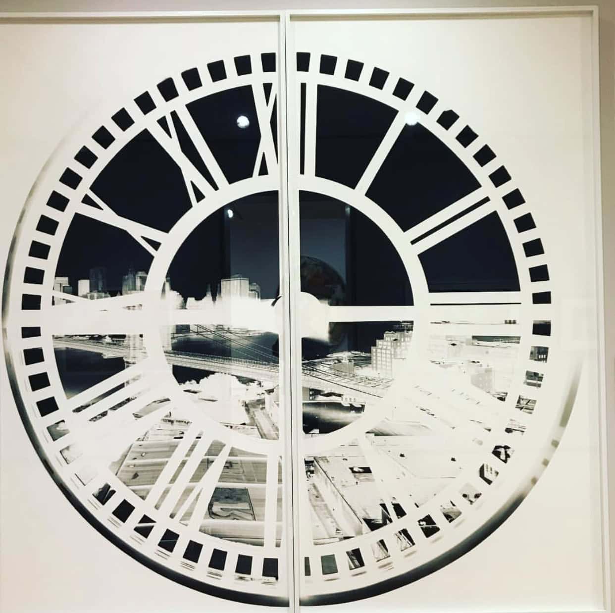 Black and white image of a clock face superimposed over an urban skyline, divided into two sections by a vertical line.
