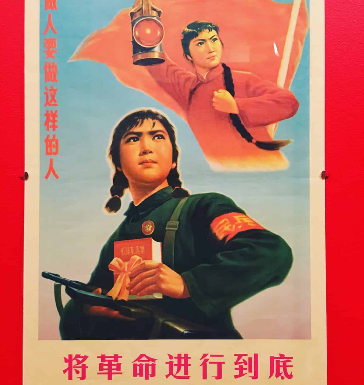 Vintage propaganda poster with a woman holding a book and rifle, another figure above with a red flag and lantern against a red background. Chinese text is present.