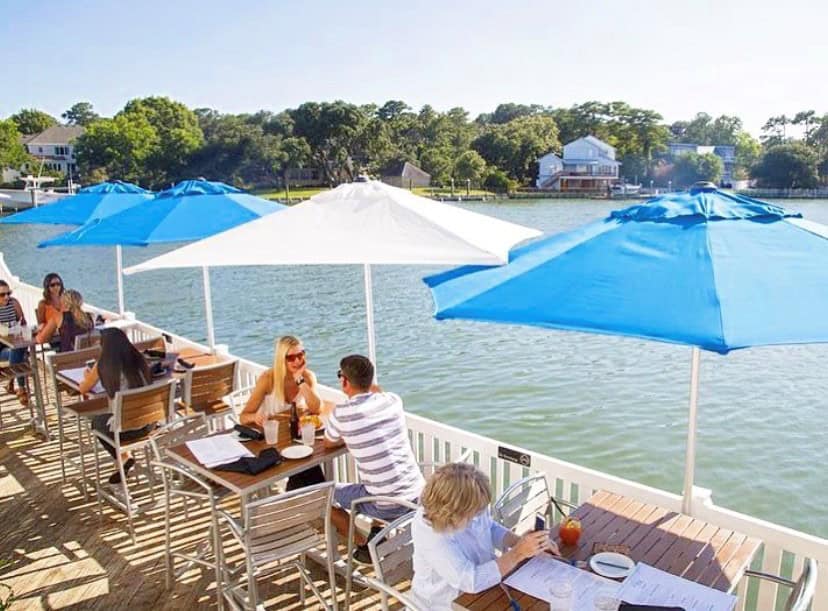outdoor seating with blue and white umbrellas along the water
