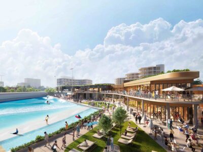 A vibrant outdoor recreation area featuring a surf pool, modern buildings, and people enjoying various activities under a sunny sky.