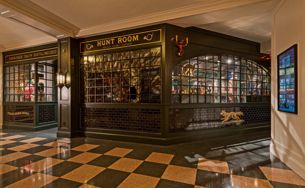 A stylish interior view of a bar area featuring "Hunt Room" and "Tarnished Truth Distilling" signs, with checkered flooring and decorative accents.