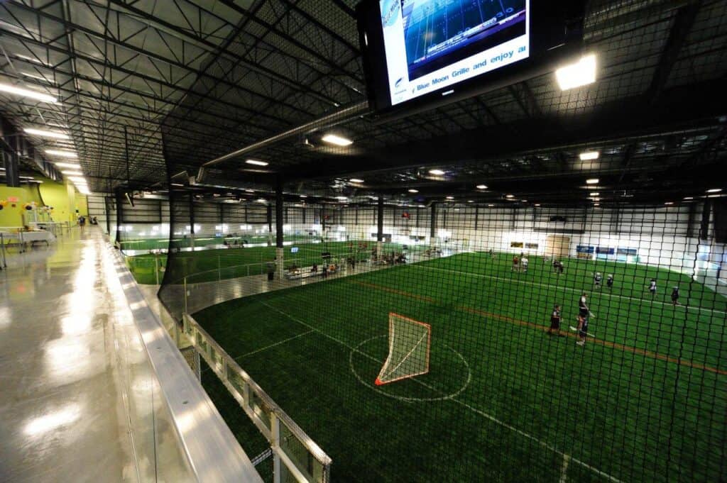 Virginia Beach Field House, an indoor sports facility featuring a turf field for soccer, with players engaged in a game and a viewing area overhead.