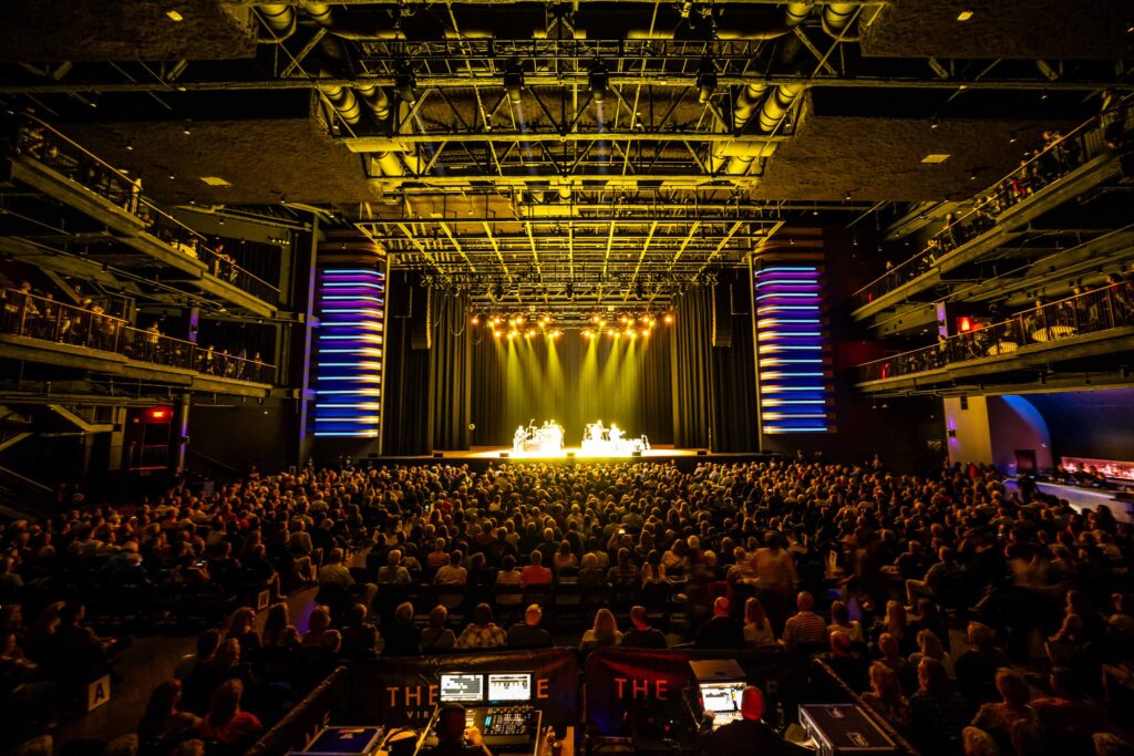 A large venue showcasing a performance on stage, with vibrant lighting and tiered seating at The Dome VB.