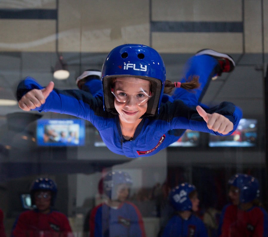 A happy young kid flying in iFly in Virginia Beach, an indoor skydiving place.