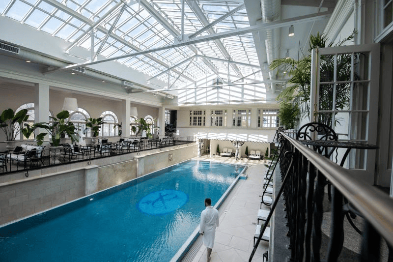 A person walking in a white robe next to an indoor pool at the Historic Cavalier Hotel & Beach Club.
