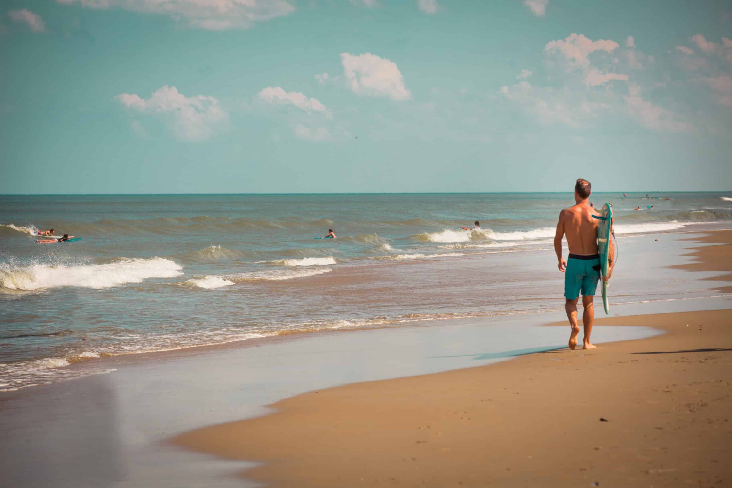 Man walking on beach with surfboard