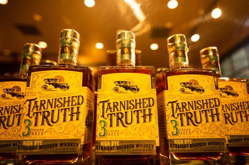 Bottles of Tarnished Truth 3-year aged high rye straight bourbon whiskey displayed on a shelf.