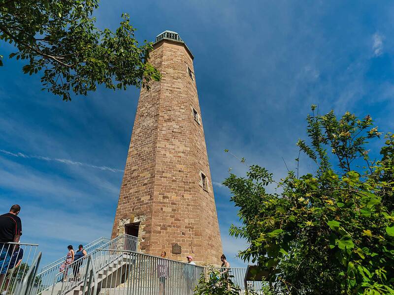 The old Cape Henry Lighthouse with people walking up and down stairs in the foreground.