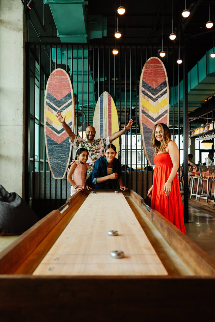 Family playing shuffle board inside of a hotel