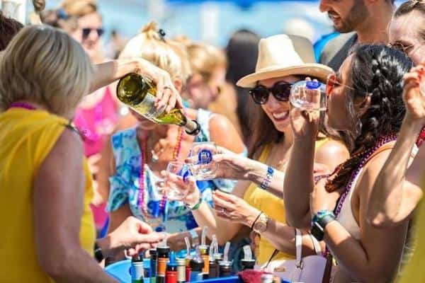 People enjoying a wine-tasting event outdoors, with a person pouring wine into glasses.