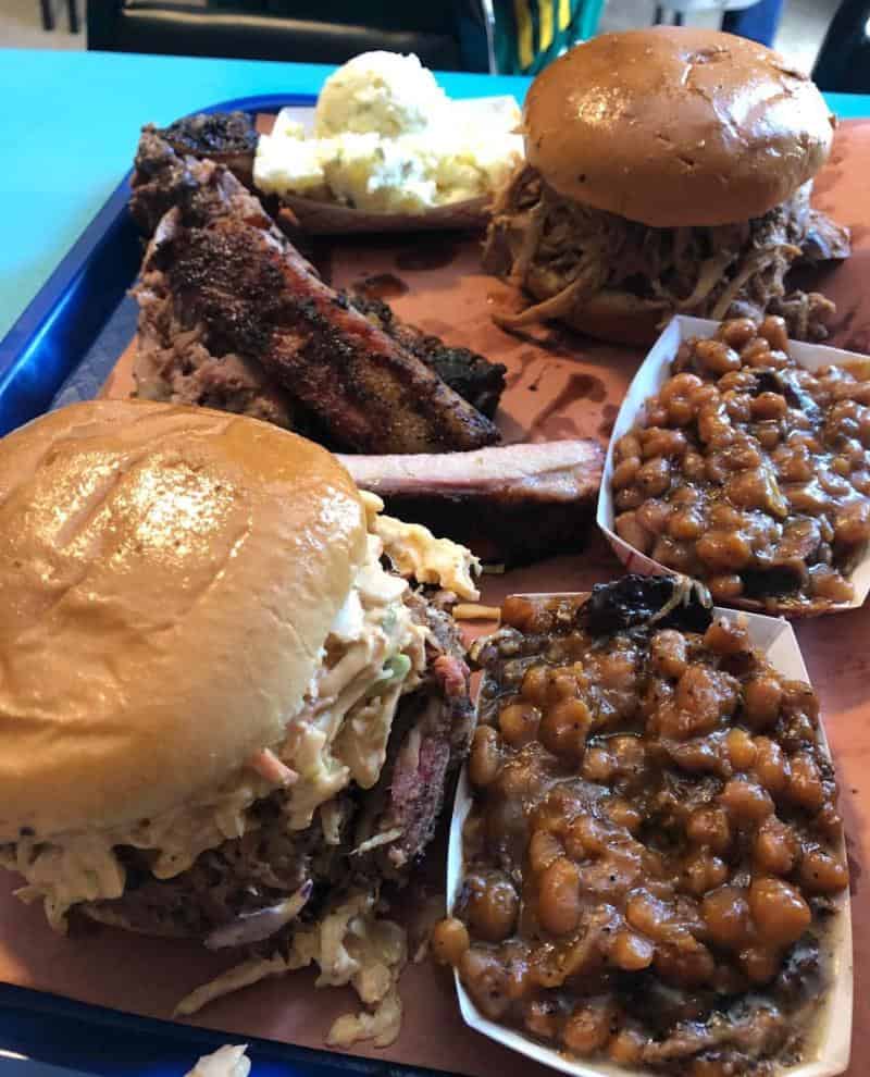 A tray with two burgers, ribs, baked beans, and potato salad.
