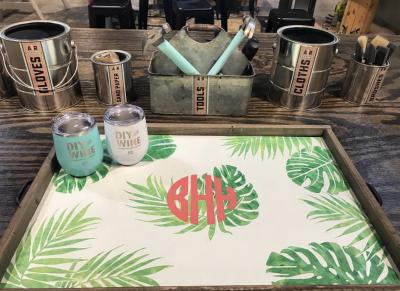 DIY craft station with labeled containers for gloves, tools, cloths, and brushes. A painted tray with a leafy design and the letters "BHY" is on display. Two "DIY Wine" tumblers included.