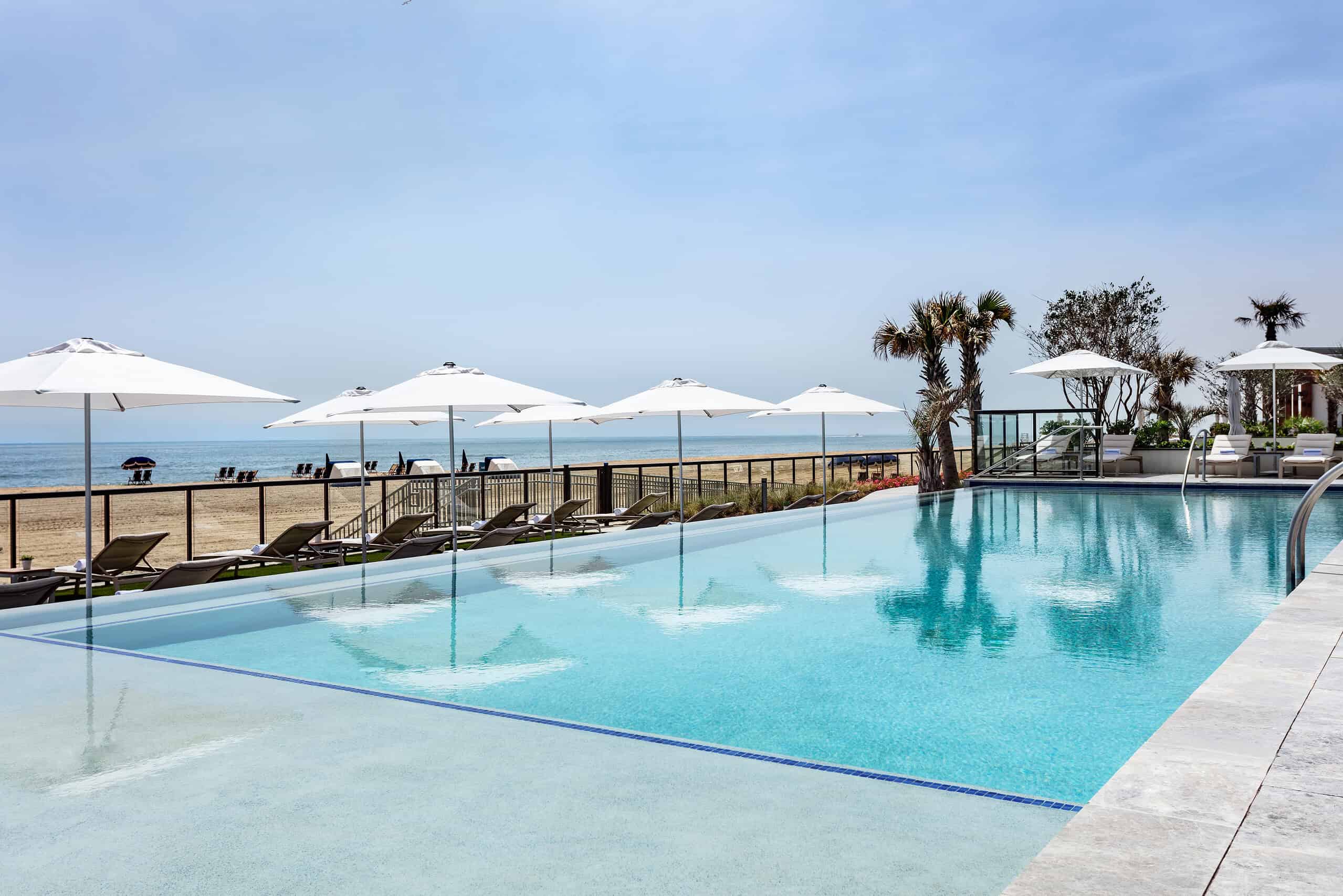 Landscape image of a pool with beach in the background