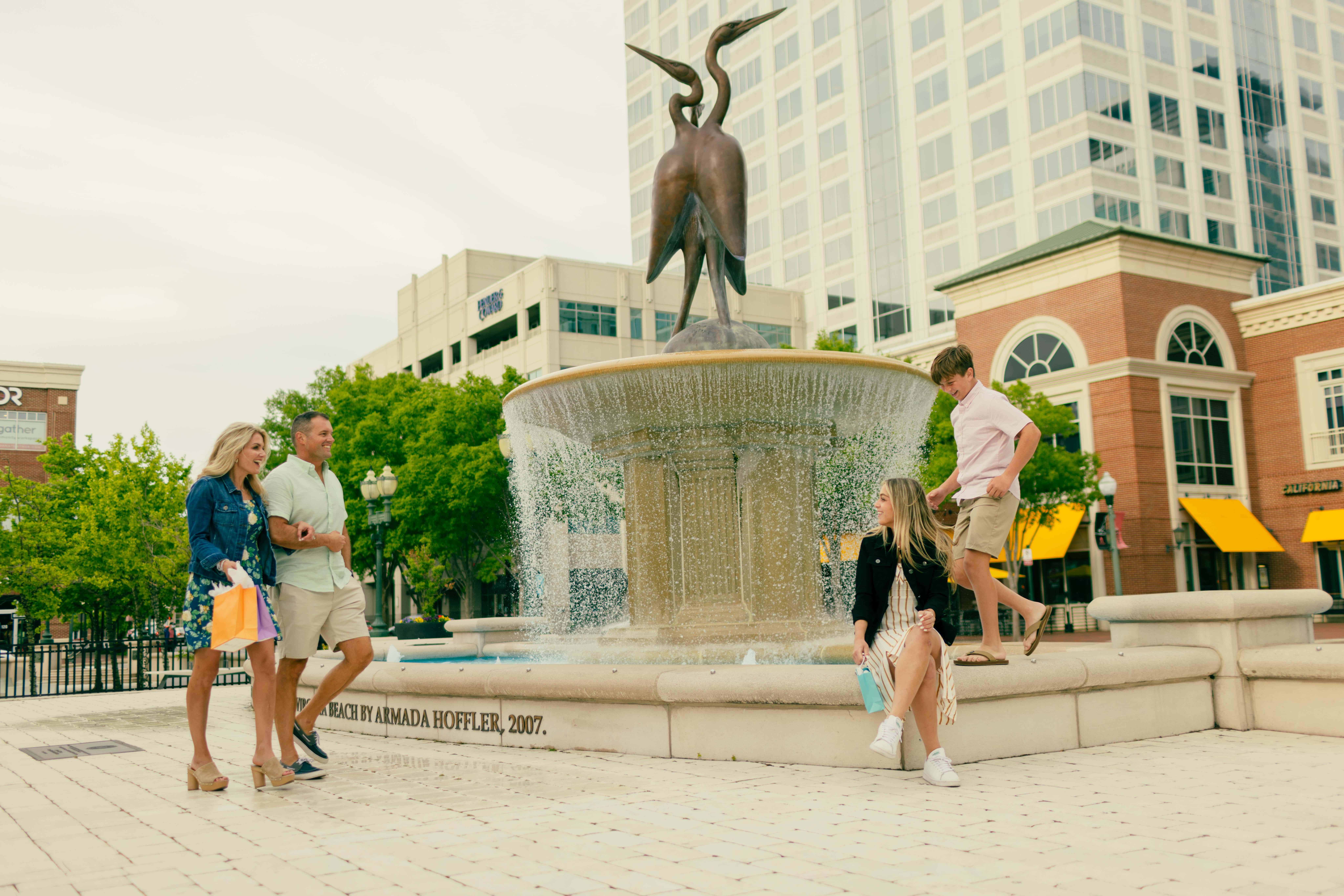 family sitting at fountain in town center