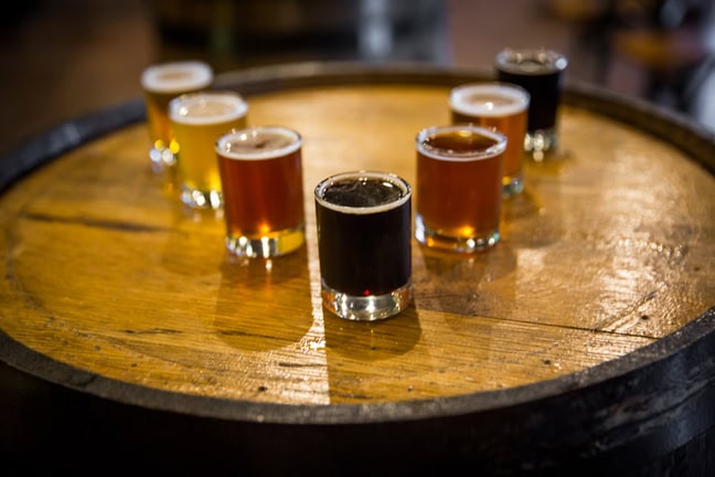 A selection of craft beer samples arranged on a wooden barrel, showcasing various colors and styles.
