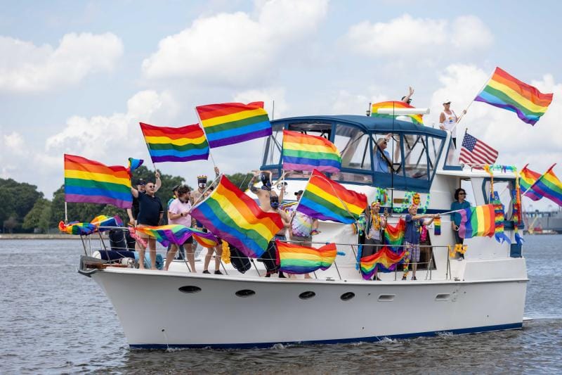 Happy people on a boat with pride flags