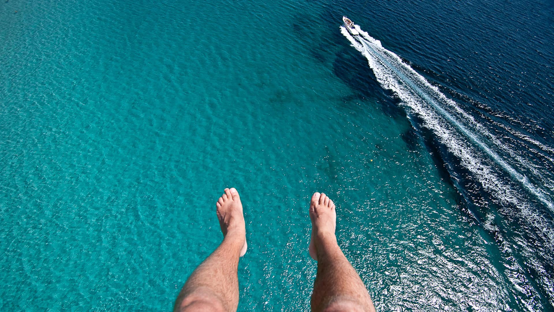 person parasailing looking down into the waters