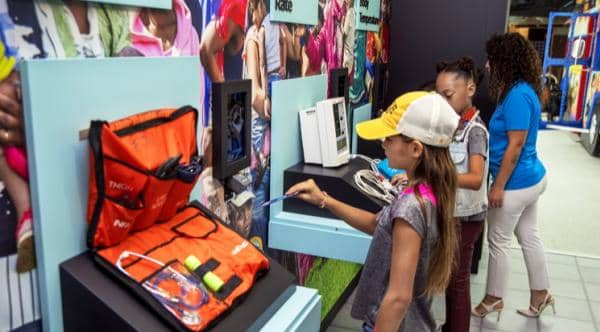 Children and an adult interact with educational displays featuring medical kits and equipment in a museum or exhibit setting.