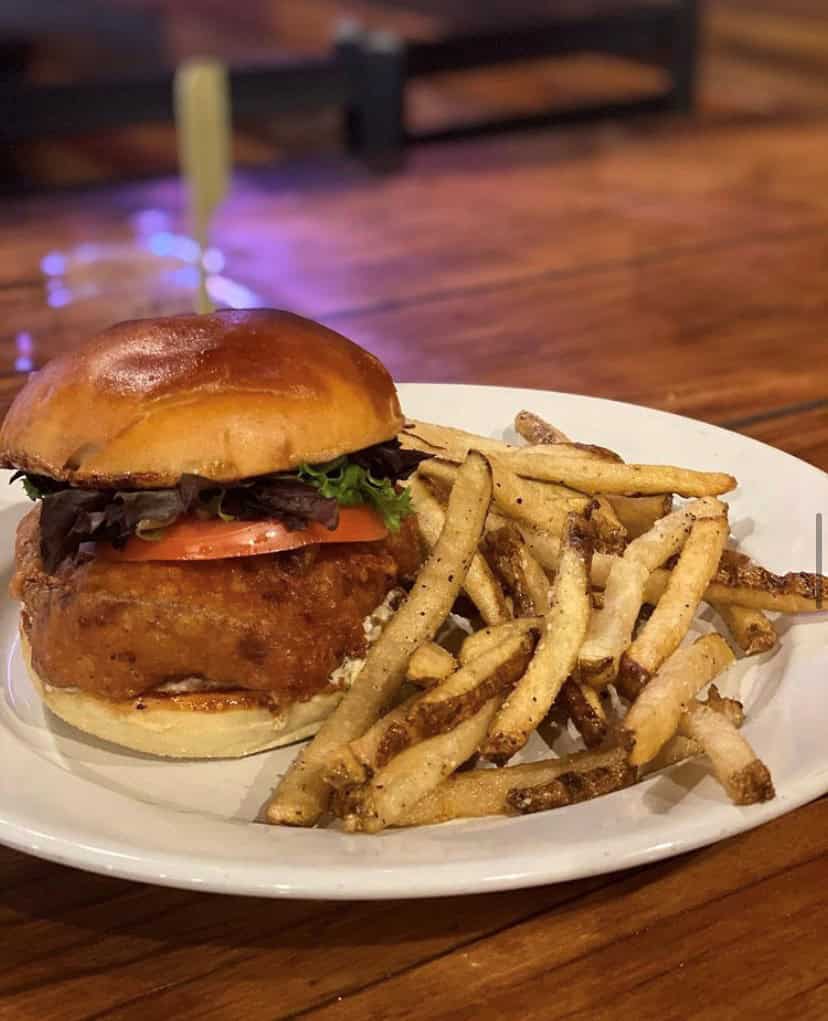 A burger with lettuce and tomato on a plate, accompanied by a serving of fries.