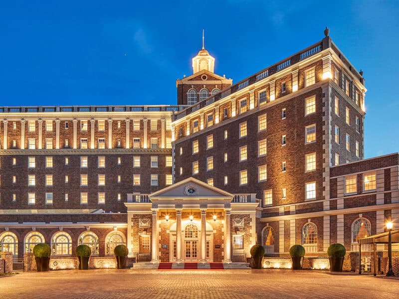 The beautifully lit historic Cavalier hotel at dusk, featuring brick architecture and elegant columns.