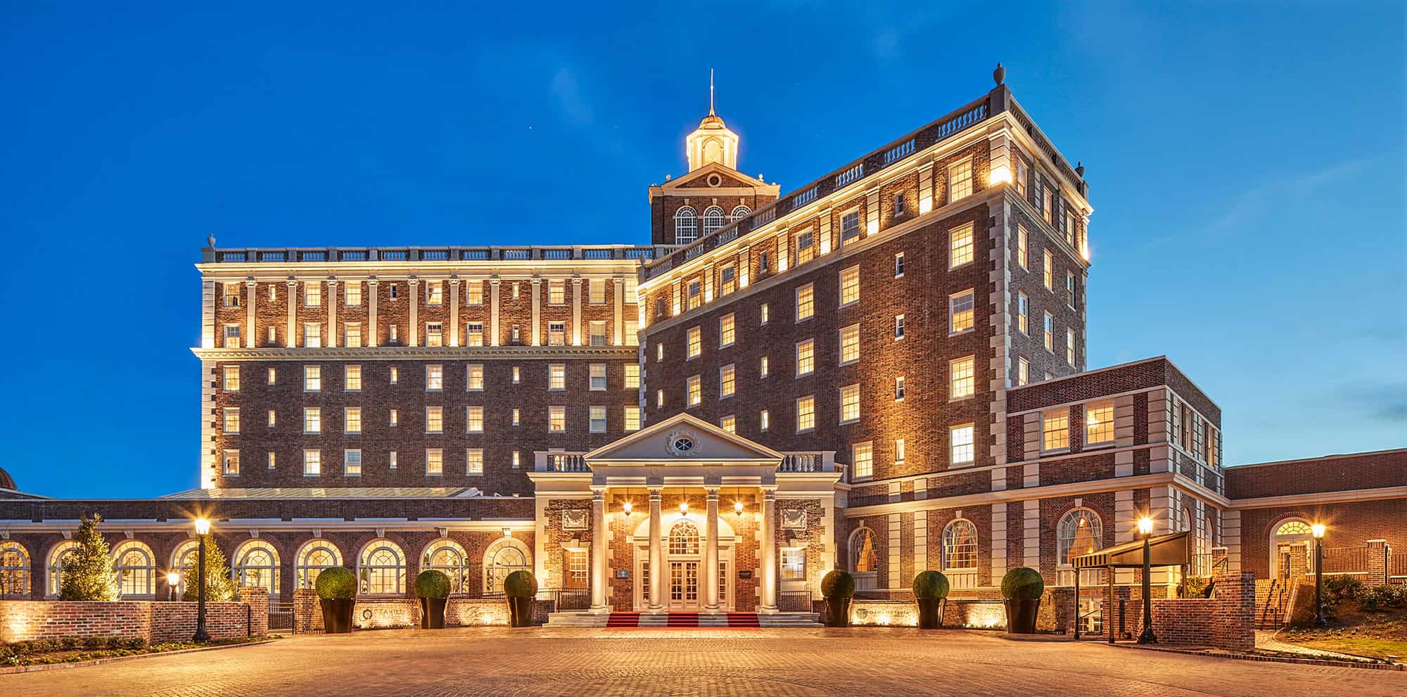 A beautifully lit historic hotel facade at dusk, featuring brick architecture and elegant columns.