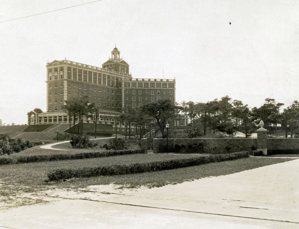 An older image of The Cavalier Hotel, a historic hotel set on landscaped grounds, featuring architectural details and surrounded by trees.