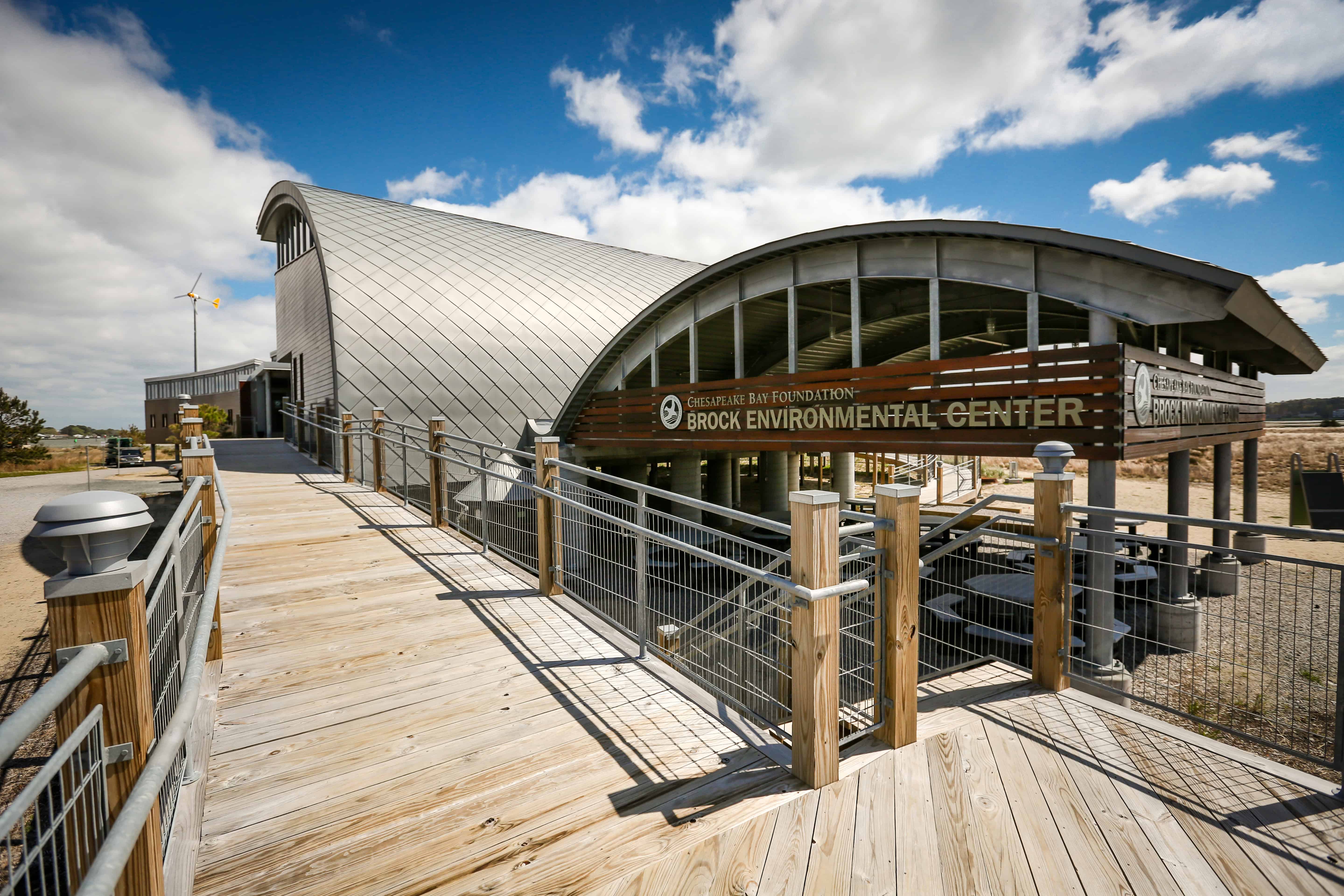 The Brock Environmental Center, featuring modern architecture and a wooden walkway, set against a cloudy sky.