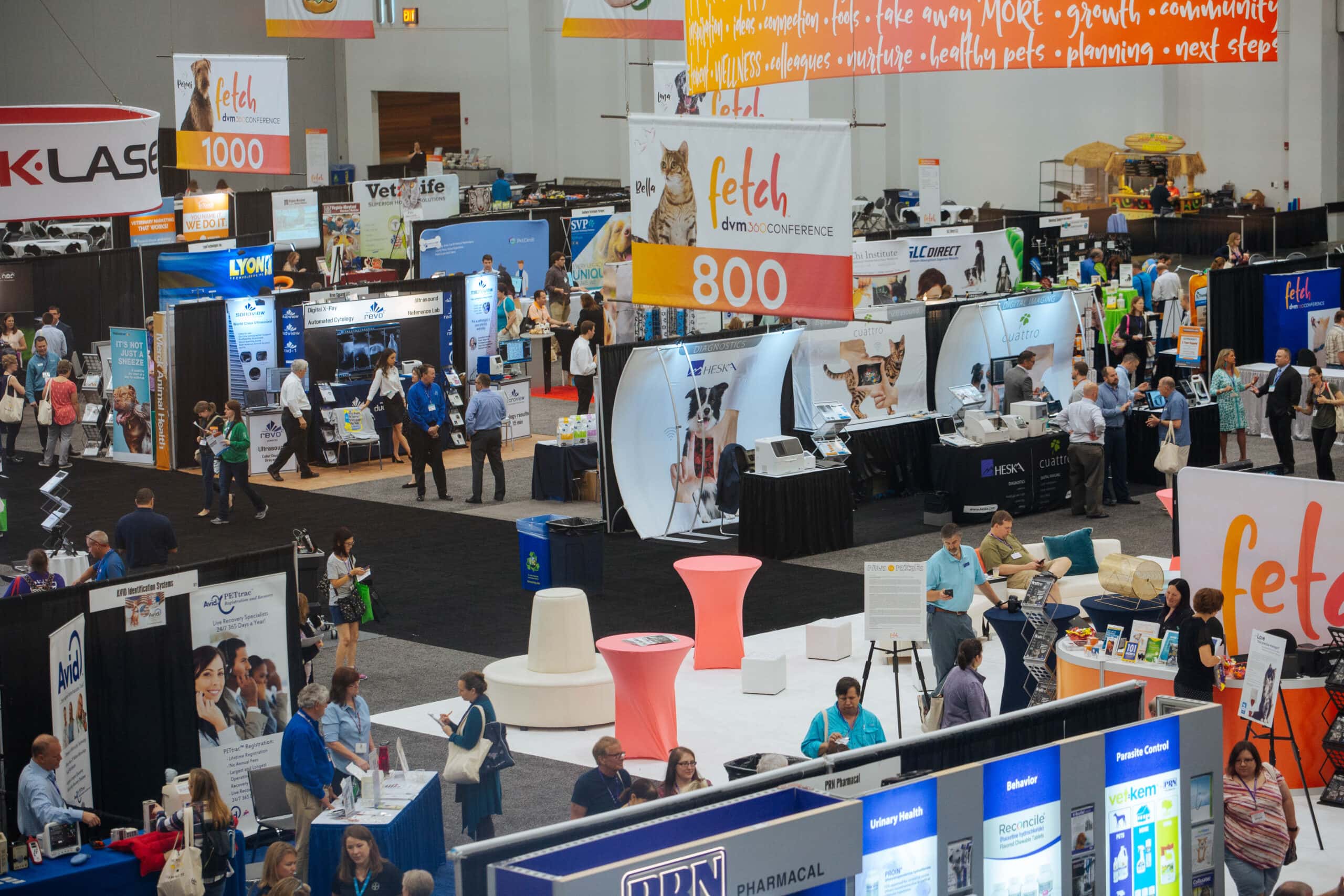 A bustling exhibition hall filled with attendees and vendor booths showcasing pet care products at the Fetch dvm360 Conference.