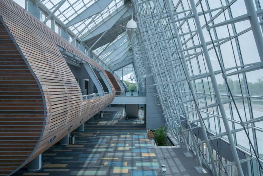 Modern architectural interior featuring a spacious, light-filled atrium with wooden elements and colorful flooring.
