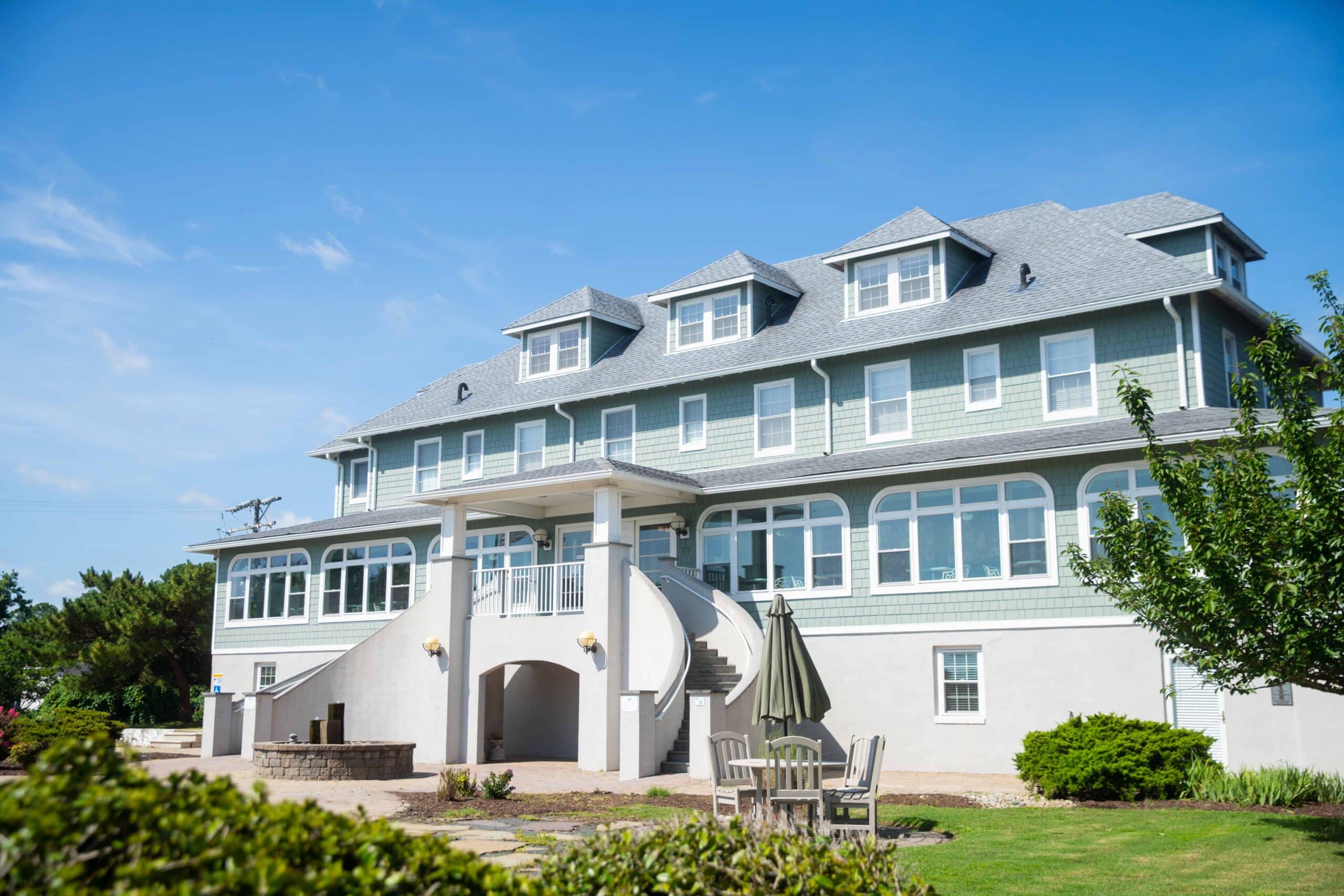 The Edgar Cayce Spa Health Center, with multiple gabled roofs, large windows, and an outdoor seating area, set against a clear blue sky.