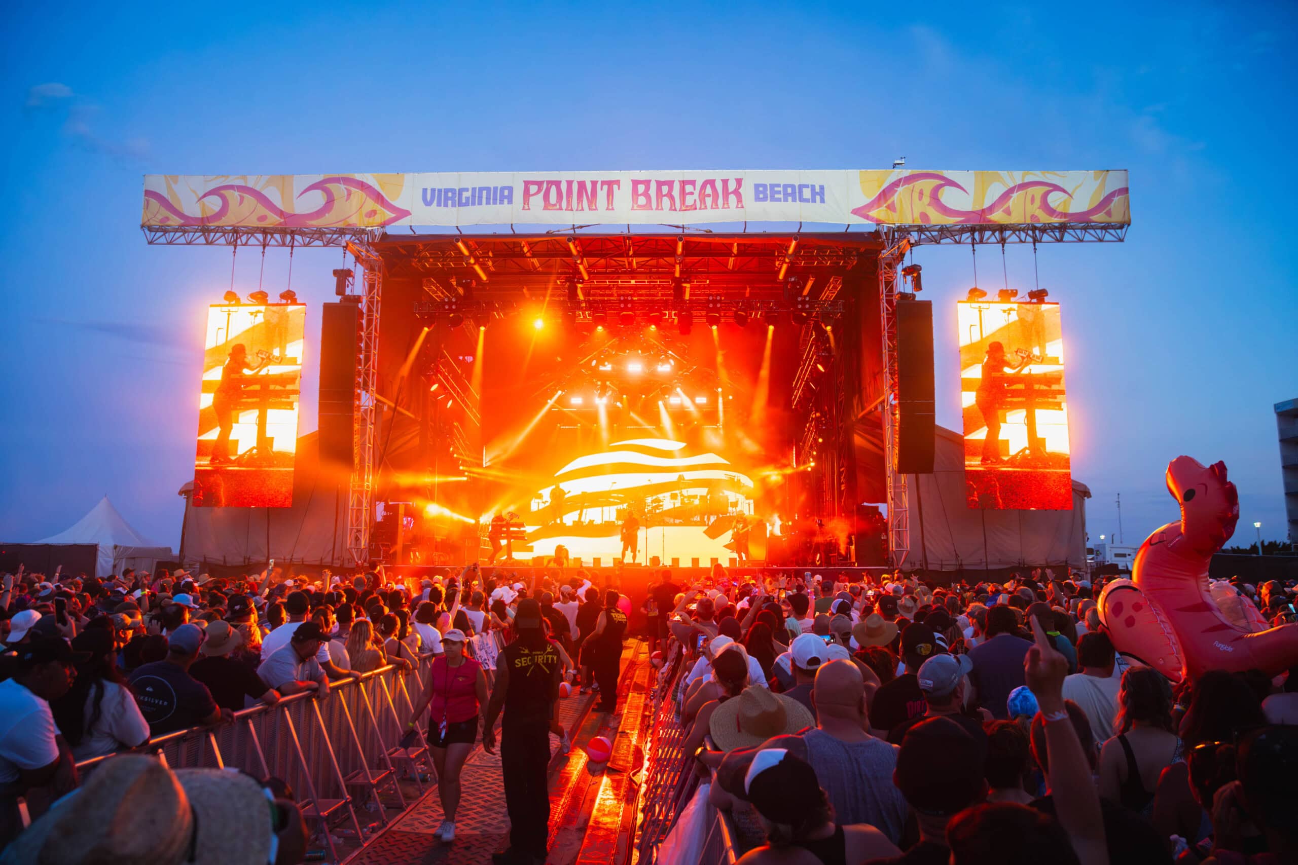 A lively music festival in Virginia Beach at Point Break Music featuring a crowded audience and a vibrant stage with dazzling lights.