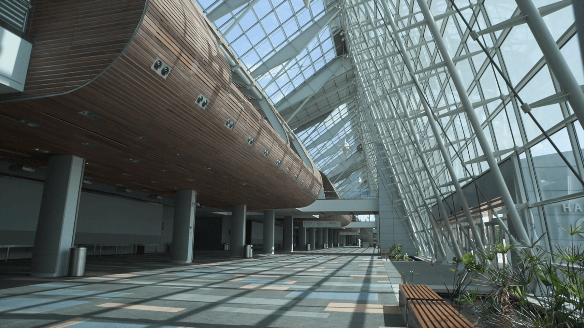 Modern architectural interior showcasing a spacious atrium with wooden details, large glass windows, and patterned flooring.
