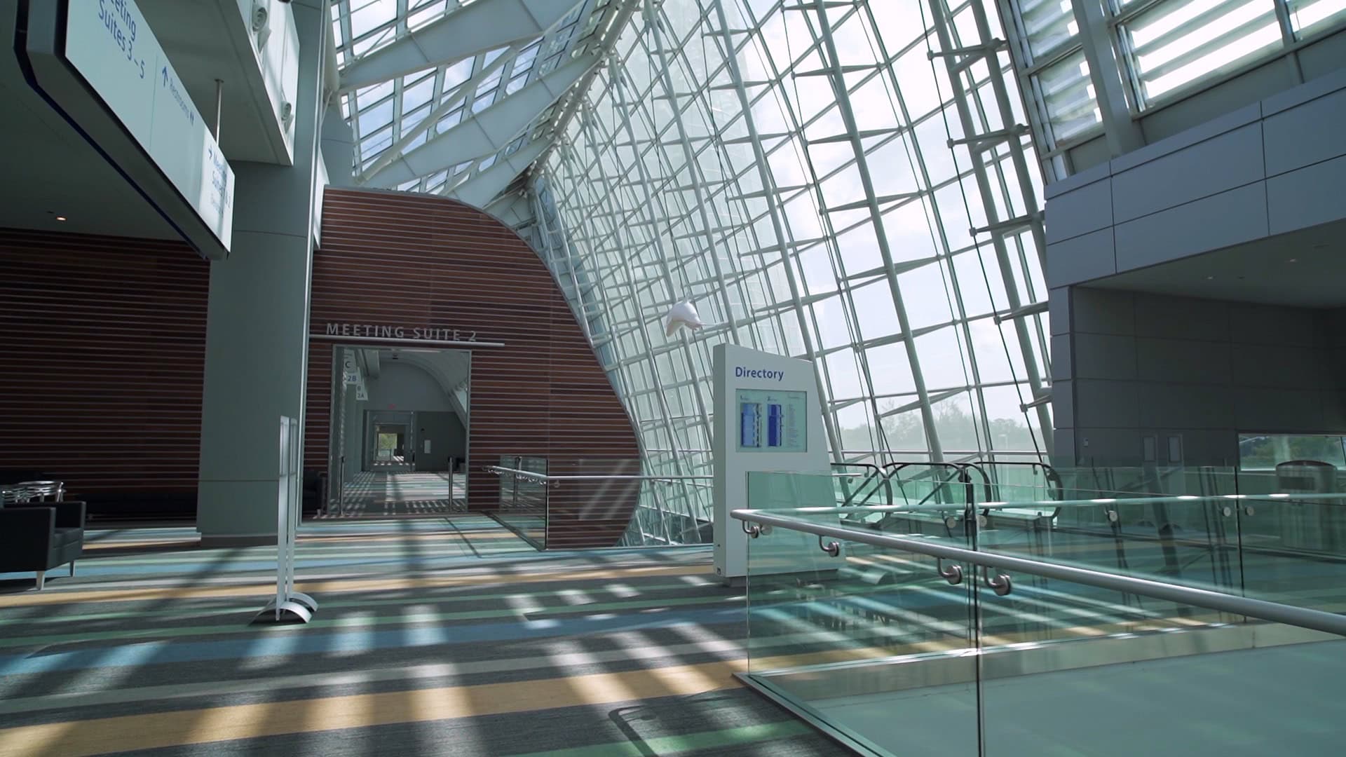 The Virginia Beach Convention Center interior featuring large glass windows, wooden accents, and signage for meeting suites and directories.