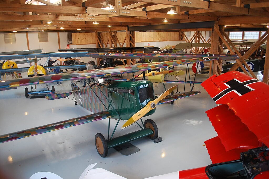 A collection of vintage biplanes displayed indoors at the Military Aviation Museum, showcasing colorful designs and historical markings in a wooden hangar.
