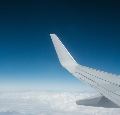 The wing of an airplane up in the blue sky above the clouds.