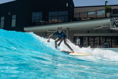 A young girl rides a human-powered wave during a surf lesson at Atlantic Park Surf in Virginia Beach.