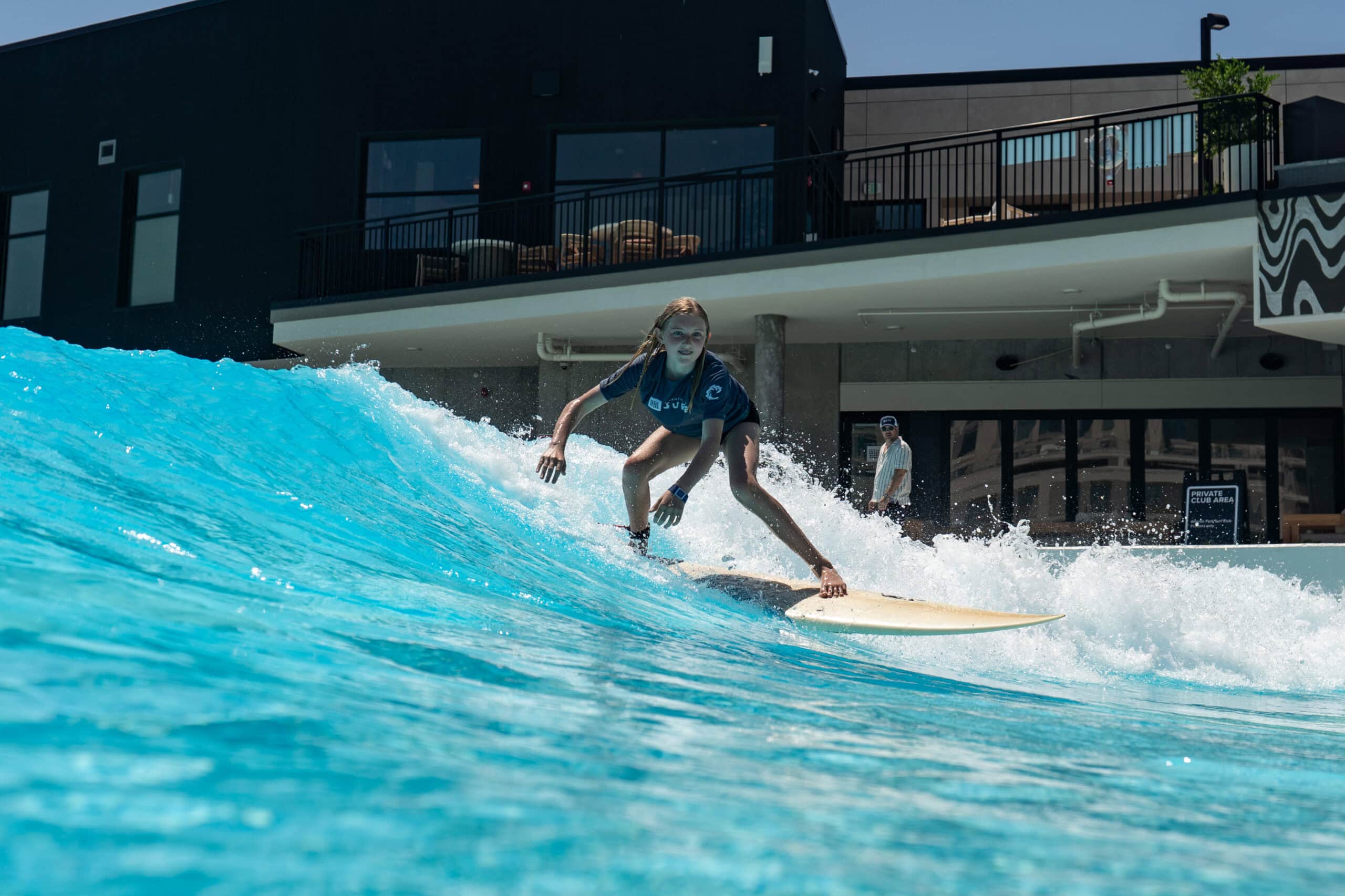 A young girl rides a human-powered wave during a surf lesson at Atlantic Park Surf in Virginia Beach.