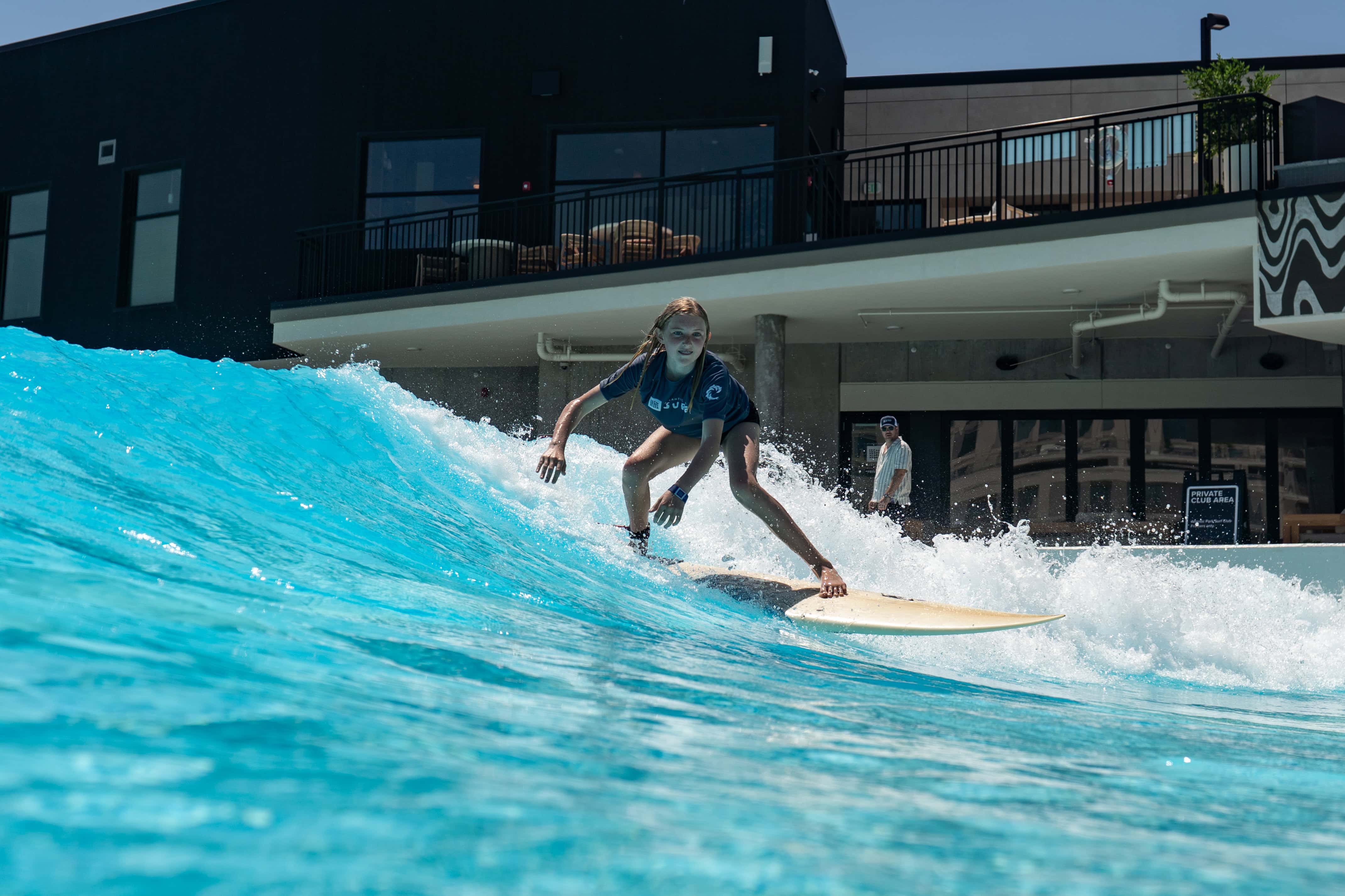 A young girl rides a human-powered wave during a surf lesson at Atlantic Park Surf in Virginia Beach. 