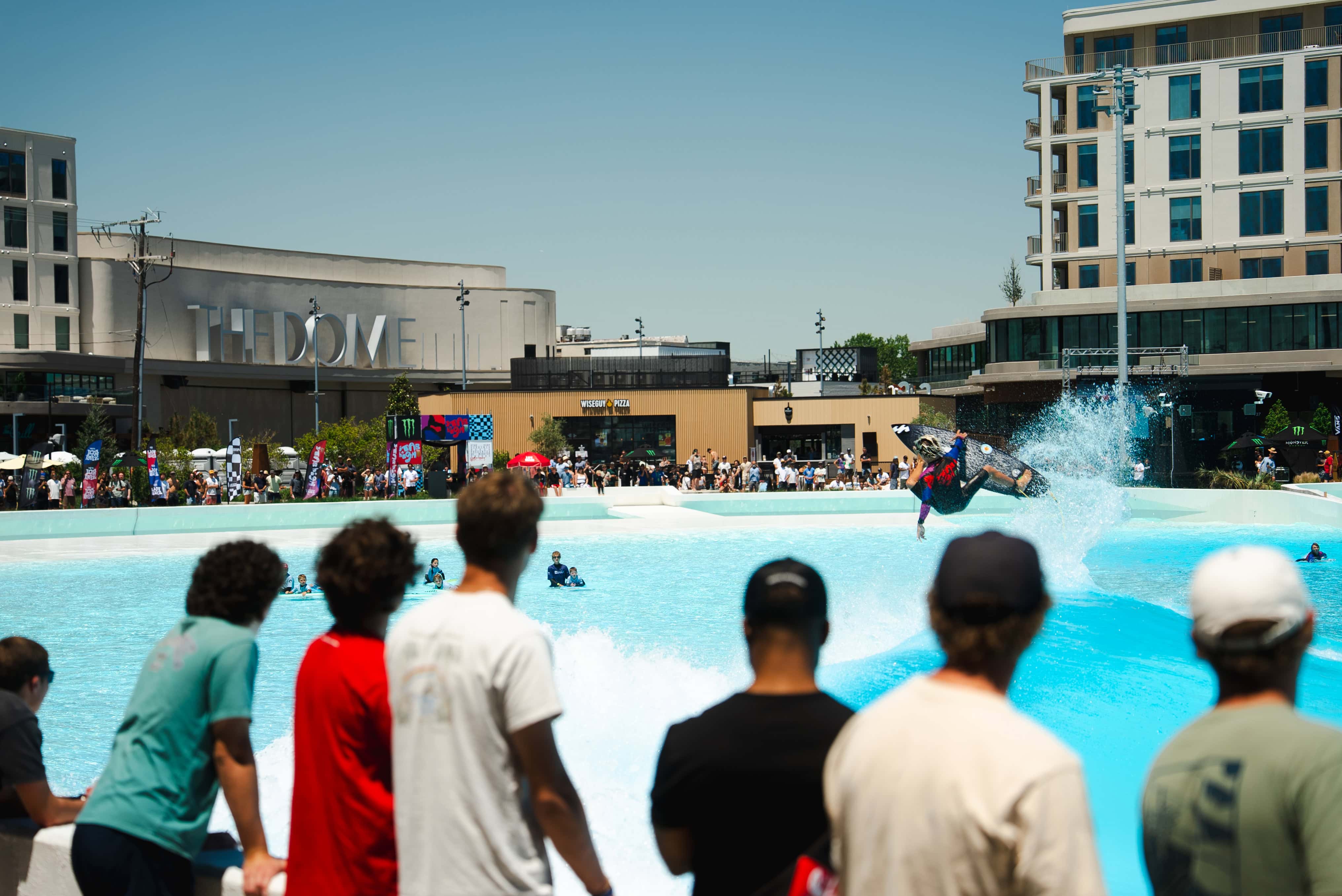 Spectators watch surfers catch a wave at Atlantic Park Surf in Virginia Beach.