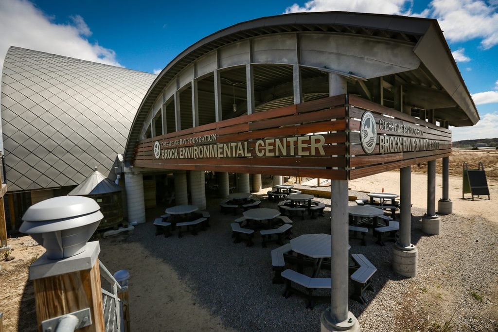 The Brock Environmental Center building with an outdoor picnic area featuring several tables under a curved metal roof.